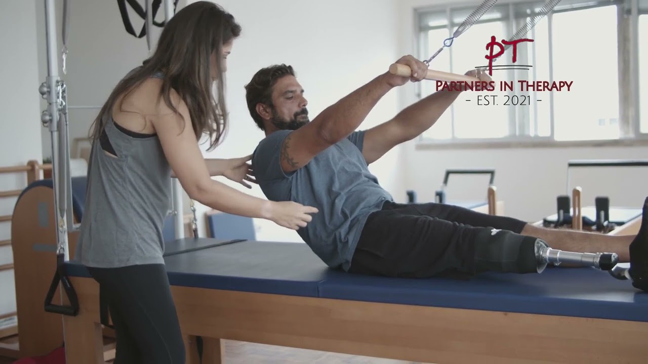 A physical therapist guiding a patient through a reformer exercise